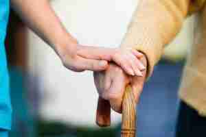 nurse holding senior hand on a walking stick