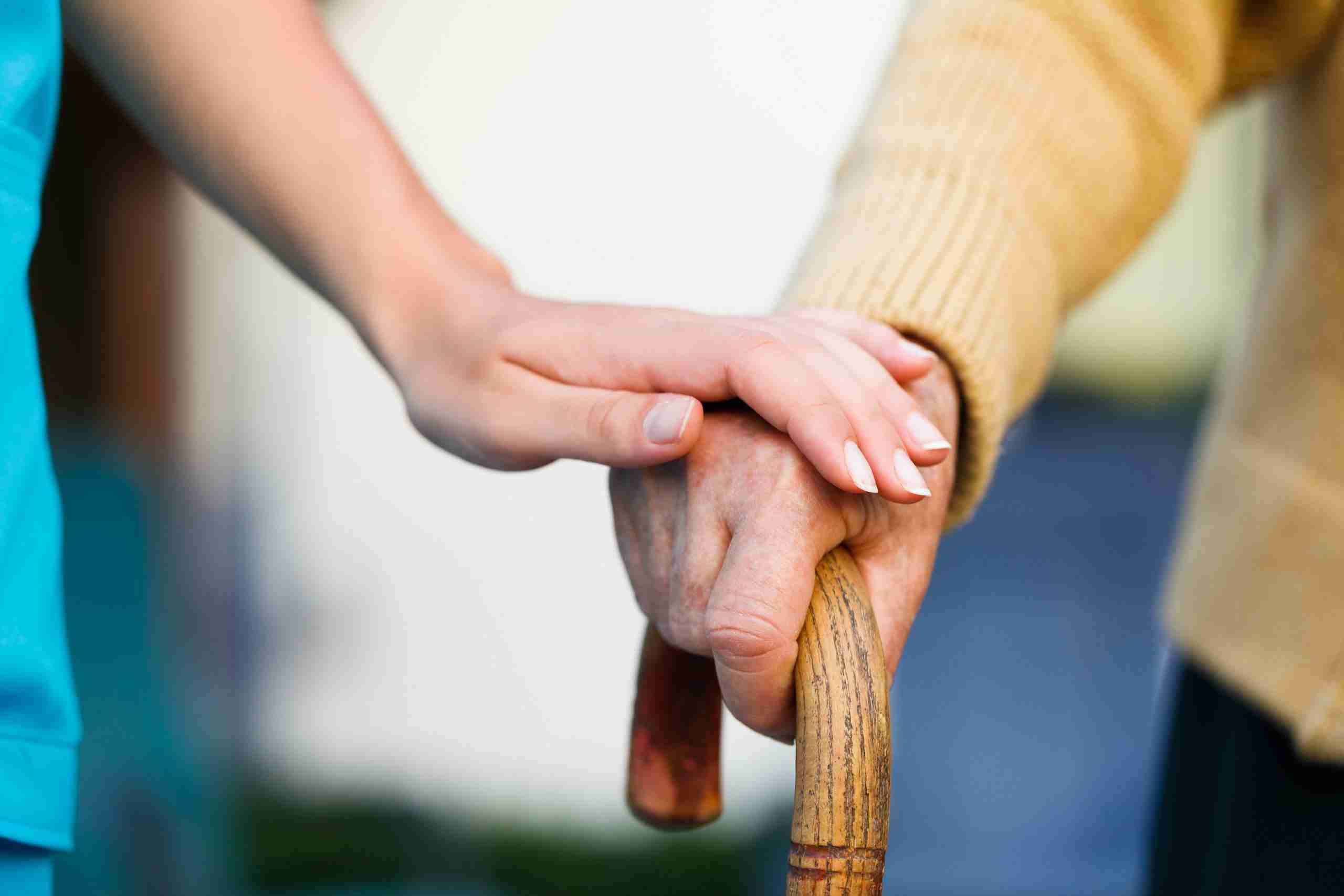 nurse holding senior hand on a walking stick