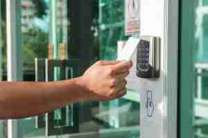 hand using keycard on electronic access control panel to enter a door
