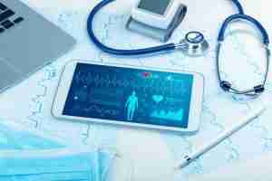 medical technology concept - charts, laptop, stethoscope, and tablet with live medical stats