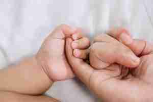 closeup of baby and mother holding hands